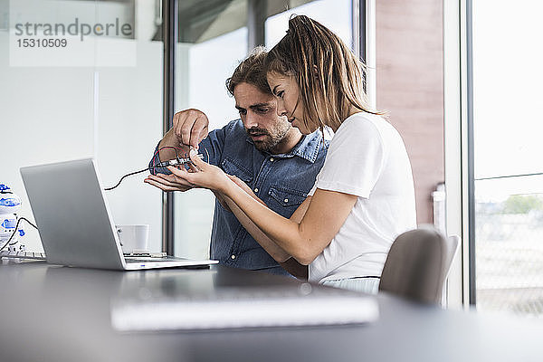 Junge Frau und Mann arbeiten an Computerausrüstung im Büro