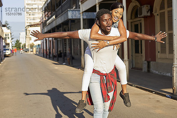 Junger Mann trägt seine Freundin huckepack auf der Straße  Mabuto  Mosambik