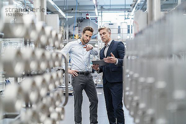 Zwei Geschäftsleute mit Tablette im Gespräch in einer modernen Fabrik