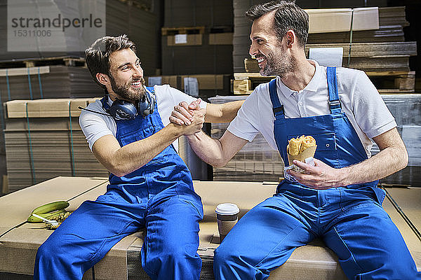 Zwei glückliche Arbeiter machen Mittagspause in der Fabrik