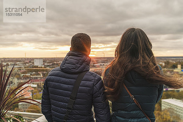 Ein Paar beobachtet den Sonnenuntergang über der Stadt von einer Aussichtsterrasse aus  Tallinn  Estland