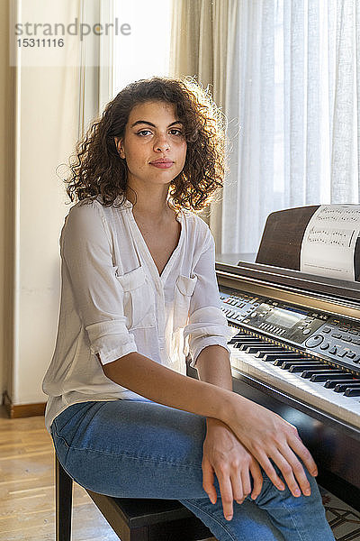 Porträt einer jungen Frau  die zu Hause am Klavier sitzt