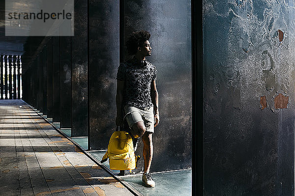 Mann mit gelbem Rucksack schaut in die Ferne  Barcelona  Spanien