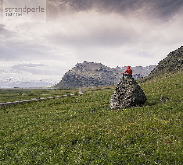 Auf einem Felsen sitzender Mann in der südlichen Region  Island