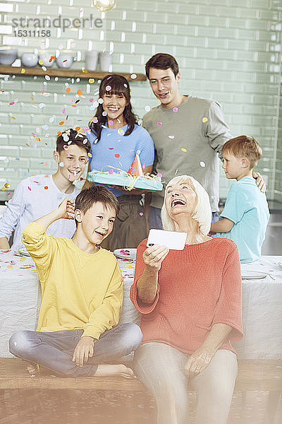 Mutter und Söhne feiern Großmutters Geburtstag in ihrer Küche  Junge nimmt sich selbst
