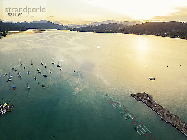 Luftaufnahme von Bootssteg und Booten am Wörthersee gegen den Himmel bei Sonnenuntergang