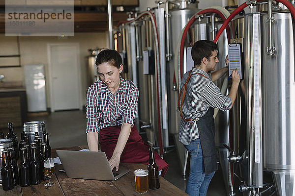 Junge Unternehmer arbeiten mit Laptop in einer Brauerei