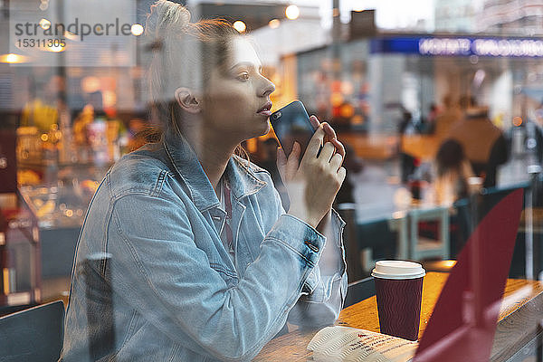 Junge Frau mit Smartphone in einem Cafe
