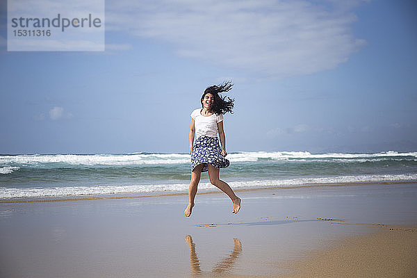 Lachende Frau springt am Strand in die Luft  Fuerteventura  Spanien