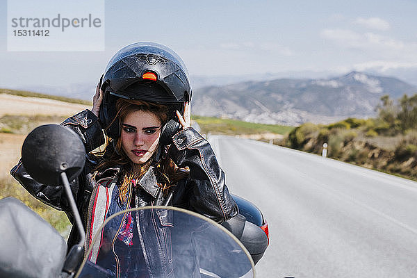 Porträt eines Motorradfahrers  der seinen Helm aufsetzt  Andalusien  Spanien