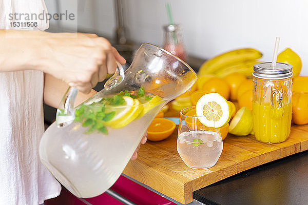 Nahaufnahme einer Frau  die zu Hause in der Küche Limonade in ein Glas gießt