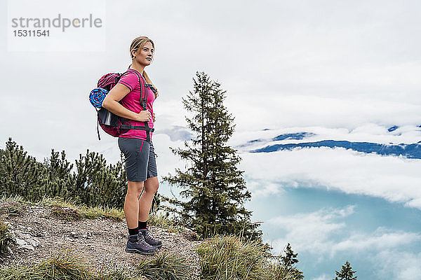 Junge Frau auf einer Wanderung in den Bergen mit Blick auf die Aussicht  Herzogstand  Bayern  Deutschland