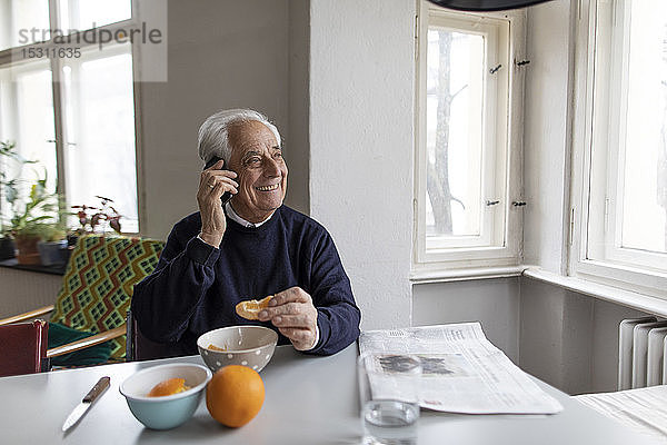 Lächelnder älterer Mann am Handy zu Hause