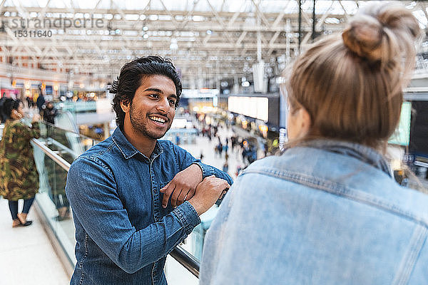 Porträt eines jungen Mannes im Gespräch mit seiner Freundin am Bahnhof