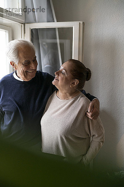 Glückliches älteres Ehepaar am Fenster zu Hause