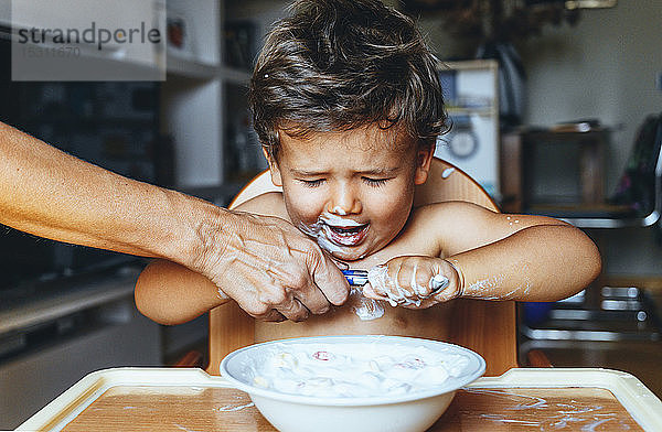 Kleiner Junge isst zu Hause Joghurt  Hand der Frau auf dem Löffel