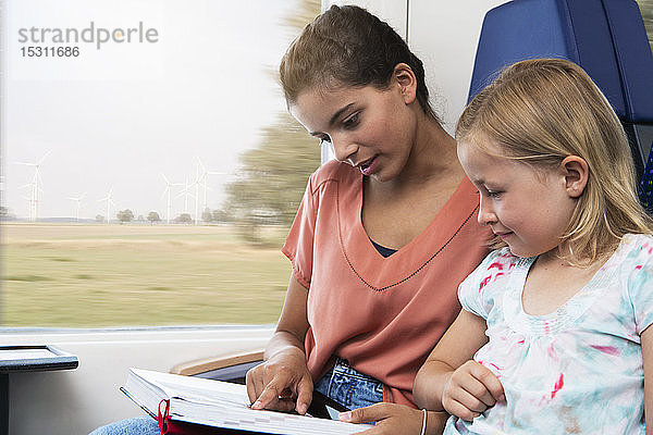 Zwei Schwestern sitzen in einem Zug und lesen ein Buch