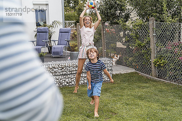 Glückliche Familie spielt Fussball im Garten