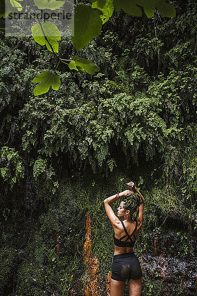 Sportliche junge Frau mit Zöpfen im Wald
