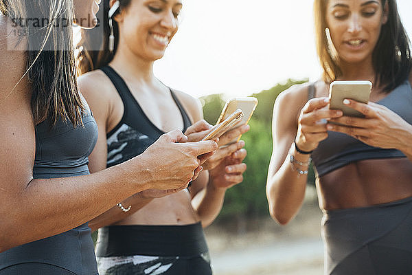 Drei Sportlerinnen benutzen nach dem Training Smartphones