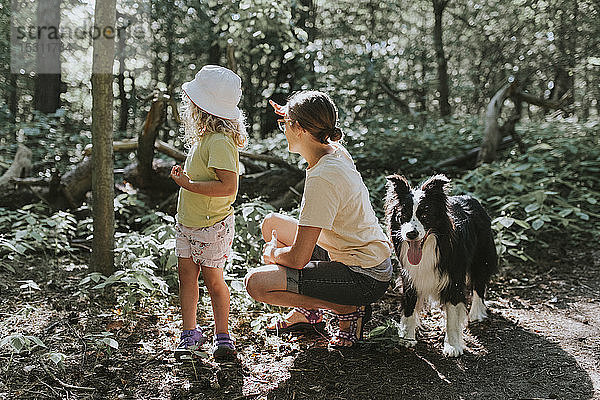 Mutter mit Tochter und Hund in einem Wald