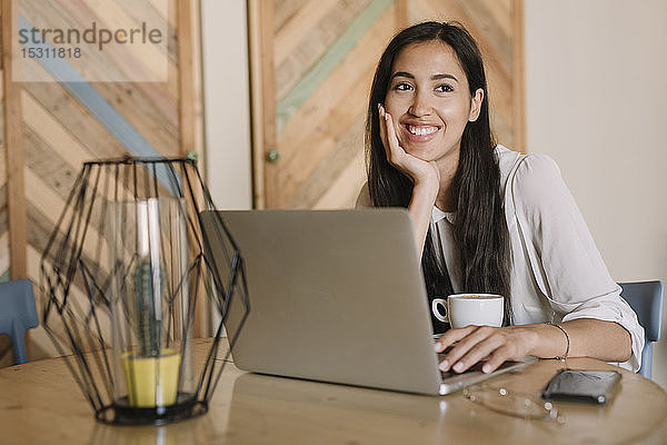 Junge Geschäftsfrau mit Laptop am Tisch in einem Café  die eine Pause macht