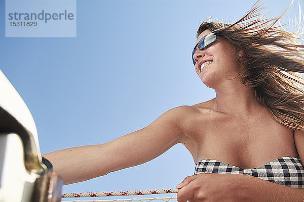 Glückliche Frau auf Segelboot vor blauem Himmel