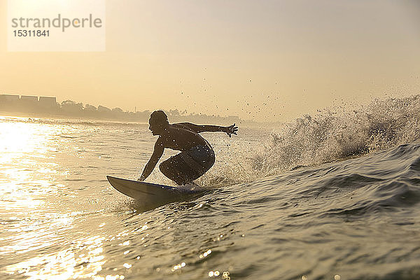 Surfer auf einer Welle bei Sonnenuntergang