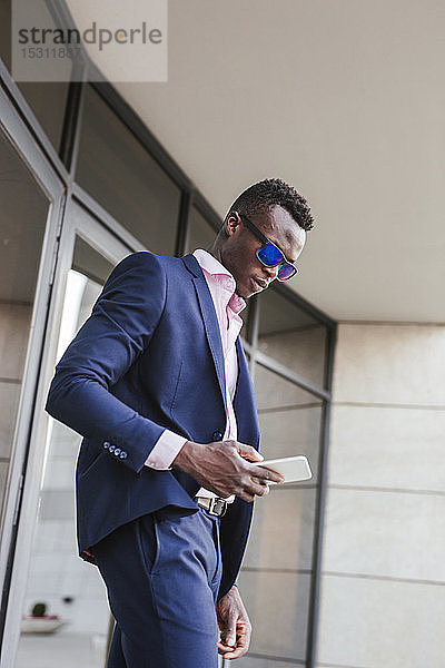 Junger Geschäftsmann benutzt draußen sein Smartphone
