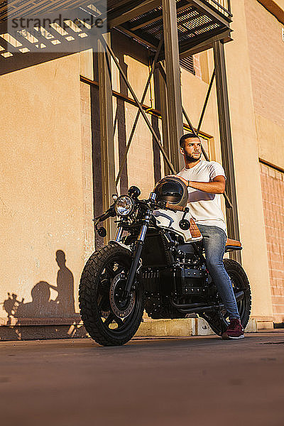 Porträt eines jungen Mannes  der auf seinem Motorrad sitzt