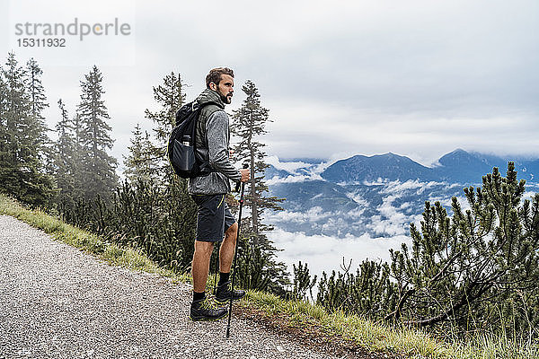 Junger Mann auf einer Wanderung in den Bergen mit Blick auf die Aussicht  Herzogstand  Bayern  Deutschland