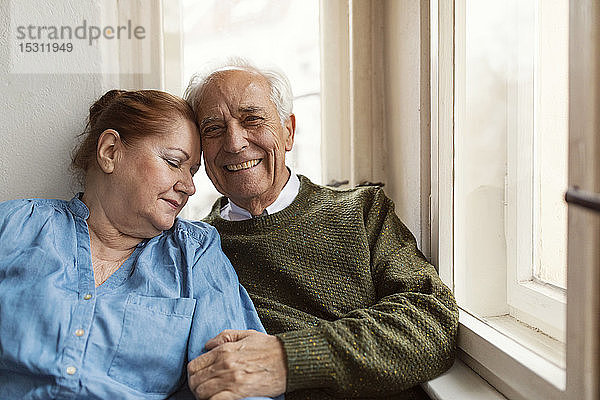 Porträt eines glücklichen älteren Ehepaares am Fenster