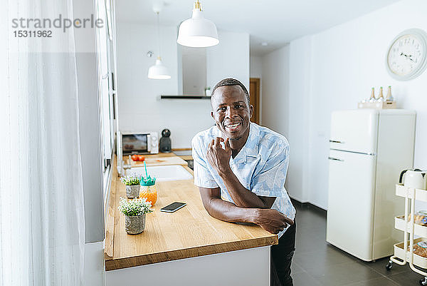 Porträt eines lächelnden jungen Mannes in der heimischen Küche