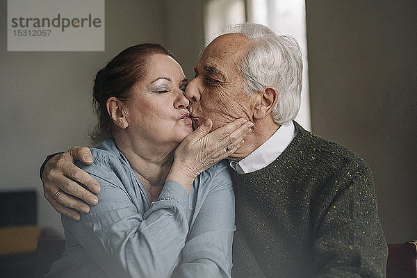 Älteres Paar küsst sich zu Hause