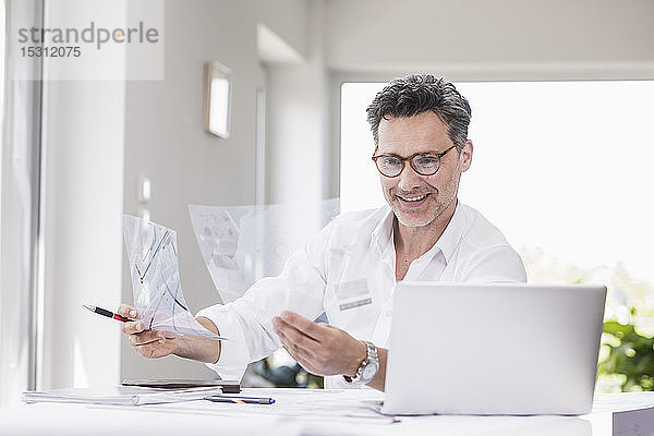 Arkitekt bereitet Präsentation vor  sitzt im Büro und betrachtet Folienplan