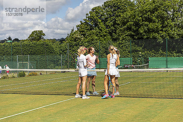 Reife Frauen beenden Tennisspiel auf Rasen