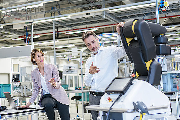 Geschäftsmann und Geschäftsfrau im Gespräch in einer modernen Fabrikhalle