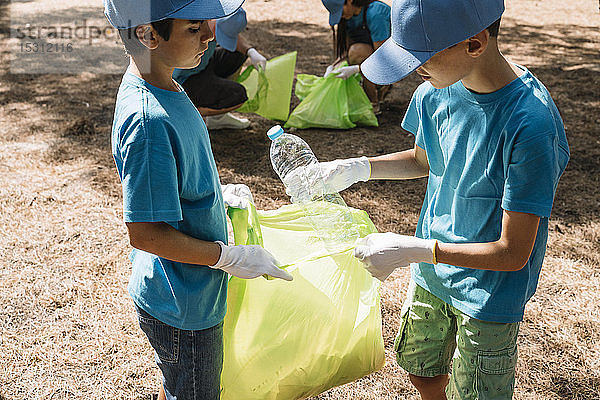 Gruppe ehrenamtlich arbeitender Kinder  die in einem Park Müll sammeln