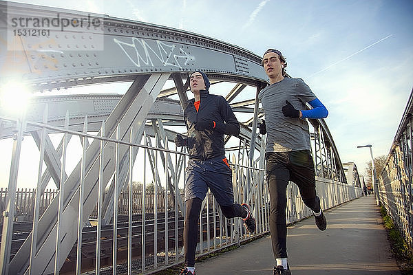 Zwei Teenager rennen über eine Eisenbahnbrücke