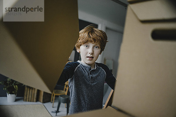 Porträt eines rothaarigen Jungen  der zu Hause mit Pappkartons spielt