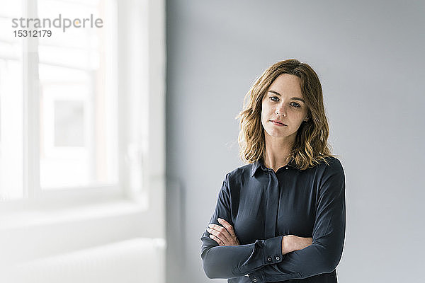 Junge Frau mit verschränkten Armen und traurigem Blick