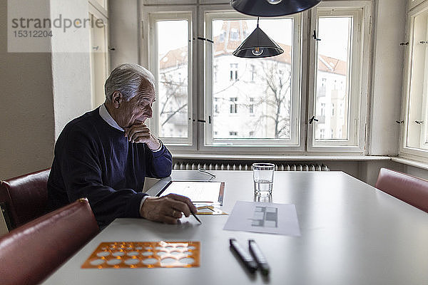 Älterer Mann benutzt Tablett mit Architekturplan
