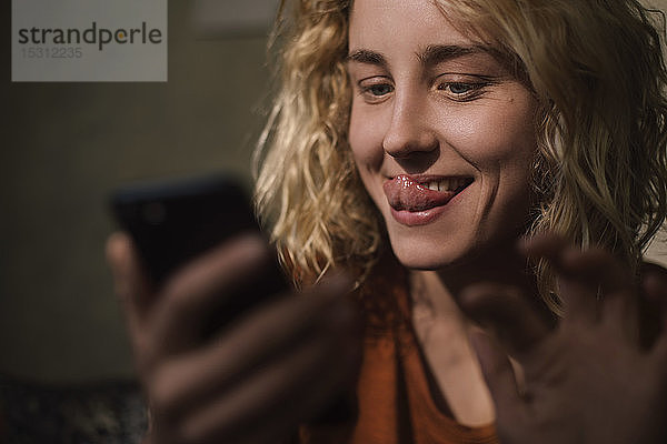 Porträt einer blonden jungen Frau  die ihr Handy für einen Video-Chat benutzt