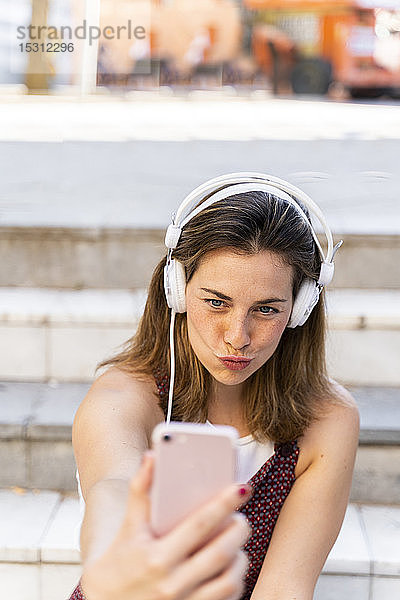 Junge Frau  die ein Smartphone benutzt  Musik hört und sich selbst eine