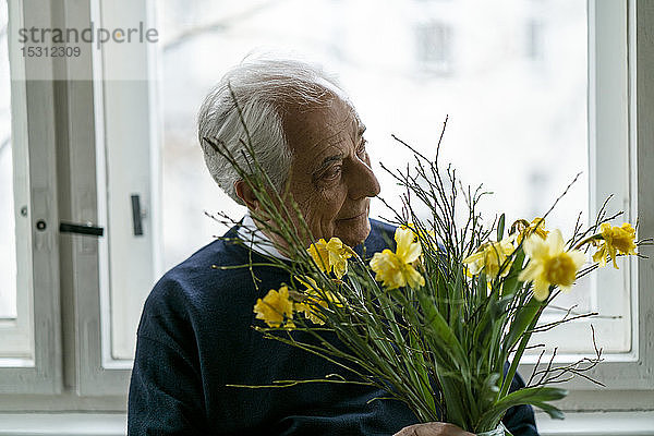 Älterer Mann mit Blumenstrauss zu Hause