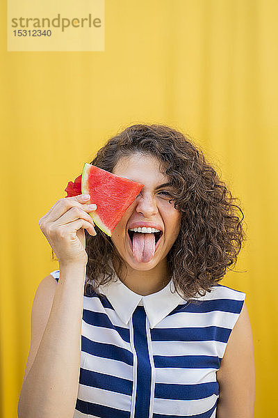 Porträt einer jungen Frau mit Wassermelone  die ihre Zunge herausstreckt