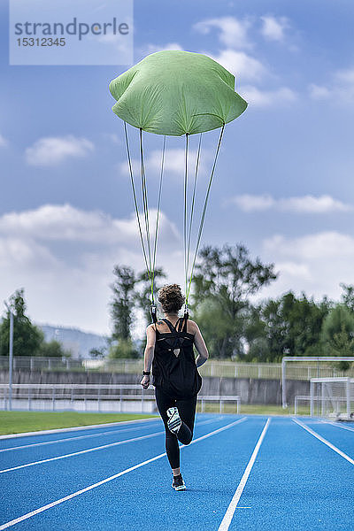 Läuferin mit Fallschirm auf Tartanbahn