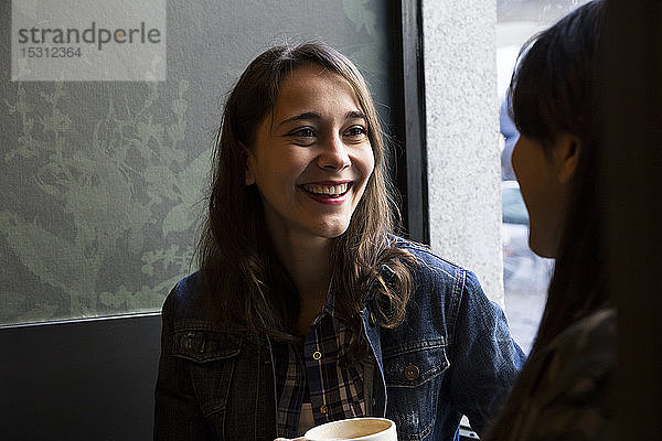 Junge Frauen sitzen im Café mit einer Tasse Kaffee