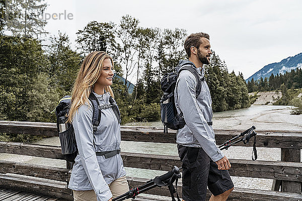 Selbstbewusstes junges Paar auf einer Wanderung zu Fuß auf einer Holzbrücke  Vorderriss  Bayern  Deutschland