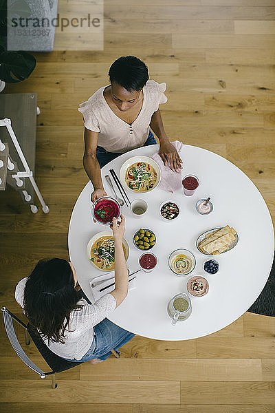 Zwei Frauen sitzen am Tisch und nehmen eine gesunde Mahlzeit ein
